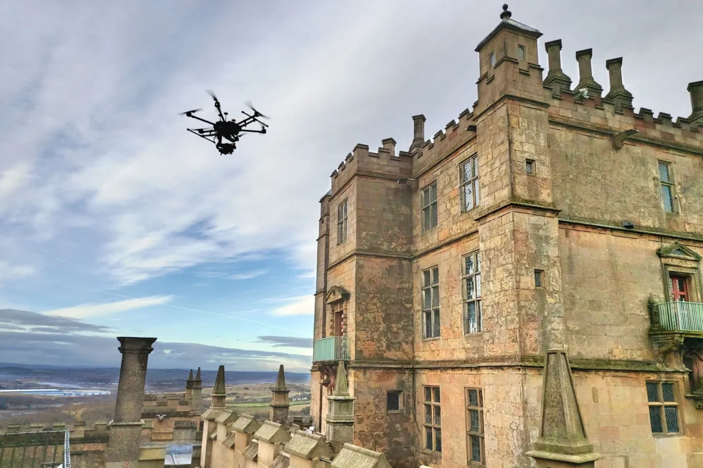 Drone flies over a large historic stone building