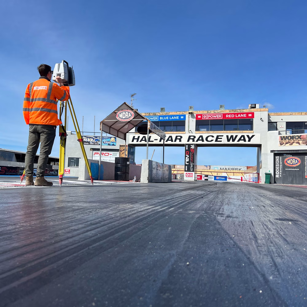 Man using a 3D Laser scanner at the start line of a drag strip on a sunny day
