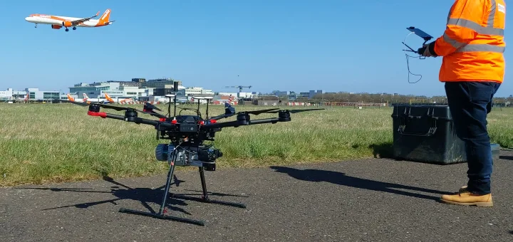 Drone with operator as a plane takes off in background